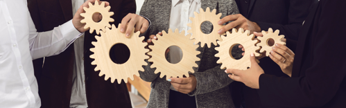 Co-workers fit wooden cogs together, demonstrating integrity