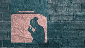 A woman's silhouette standing in a window, placing her head in her hands