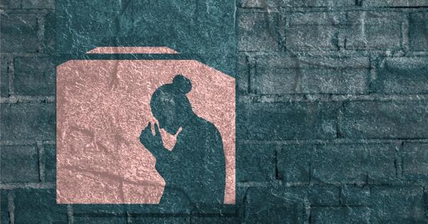 A woman's silhouette standing in a window, placing her head in her hands