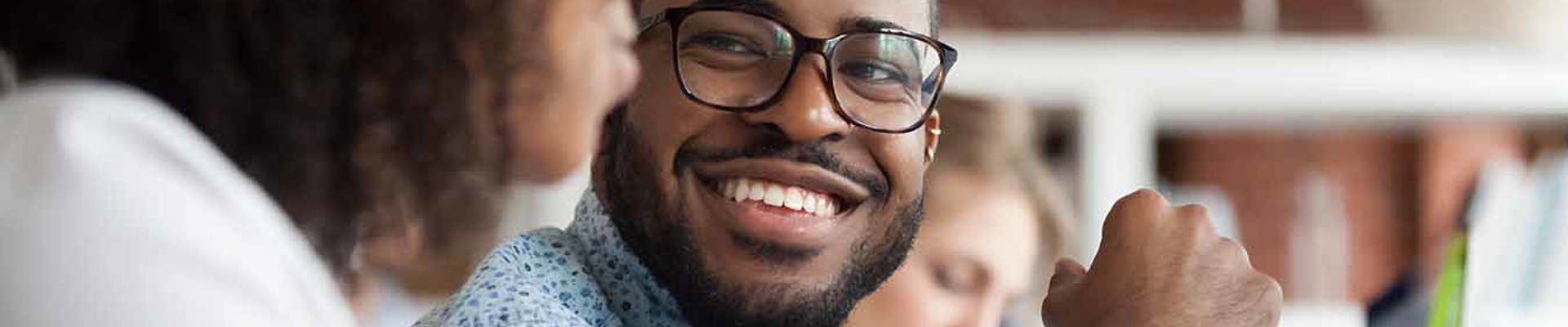 Decorative stock image of two people talking side by side sat at a desk